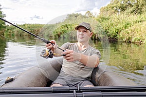 Young male fisherman in a boat with a fishing rod