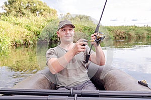 Young male fisherman in a boat with a fishing rod