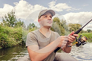 Young male fisherman in a boat with a fishing rod