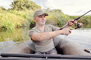 Young male fisherman in a boat with a fishing rod