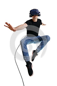 Young male flying on white backgroung like superhero while looking in VR goggles