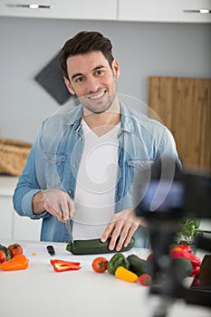 young male food blogger recording video in kitchen