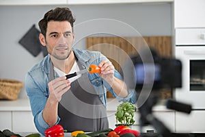 young male food blogger recording video in kitchen