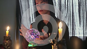 Young male fortune teller performing ritual with crystal ball foreseeing future