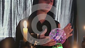 Young male fortune teller performing ritual with crystal ball foreseeing future