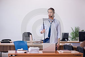 Young male furious employee holding axe in the office photo