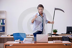 Young male furious employee holding axe in the office photo