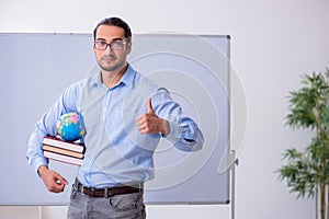 Young male geography teacher in front of whiteboard