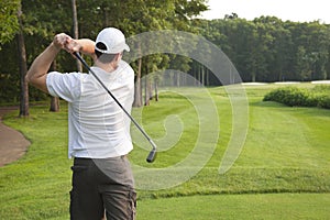 Young male golfer tees off on a par three photo