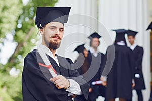 A young male graduate against the background of university graduates.