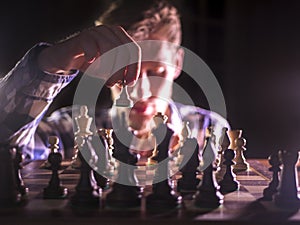 Young male grandmaster hand making next move playing chess in dark place on tournament