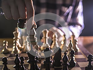 Young male grandmaster hand making next move playing chess in dark place on tournament