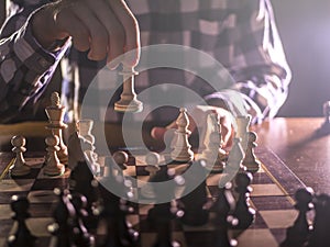 Young male grandmaster hand making next move playing chess in dark place on tournament