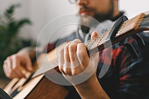 Young guitarist hipster at home with guitar capo close-up