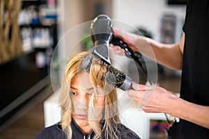 Young male hairdresser is drying young woman hair
