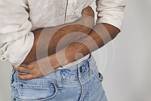 Young male having painful stomachache on white background- abdomen bloating concept