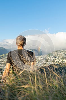 Young male hiker sitting on the summit of Diamond Head Crater in Honolulu on the Island of Oahu, Hawaii