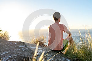 Young male hiker sitting on the summit of Diamond Head Crater in Honolulu, Oahu, Hawaii, looking down to Waikiki Beach and the cit