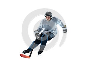 Young male hockey player with the stick on ice court and white background