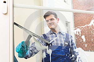 Housekeeper Cleaning Window With Squeegee