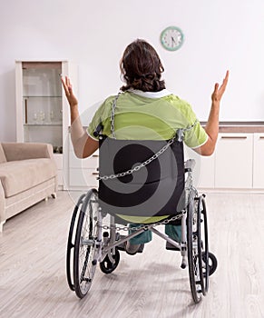 Young male invalid in wheel-chair suffering at home