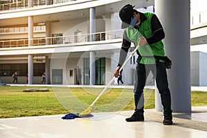 Young Male Janitor Cleaning Floor With Mopping  on modern building photo