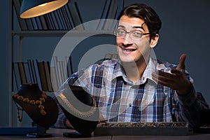 The young male jeweller working at night in his workshop