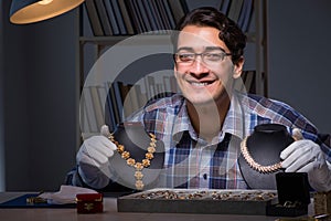 The young male jeweller working at night in his workshop