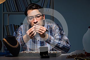 The young male jeweller working at night in his workshop