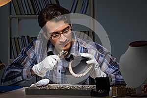 The young male jeweller working at night in his workshop