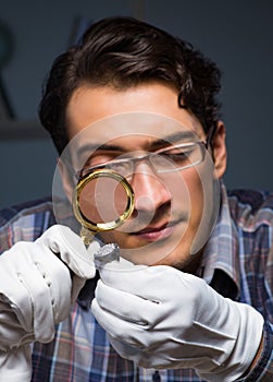 Young male jeweller working at night in his workshop