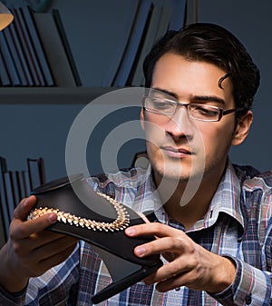 Young male jeweller working at night in his workshop