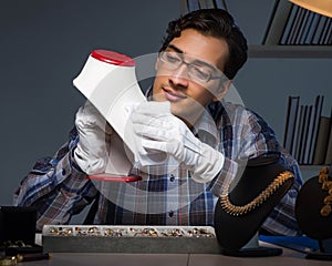 Young male jeweller working at night in his workshop