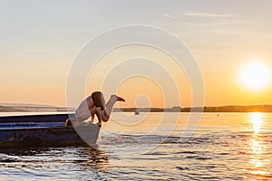 Young male jumping into the Danube river from the boat during scenic sunset in Serbia