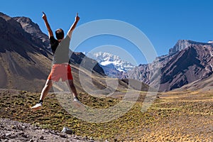 Young male jumping for joy at the entrance to Aconcagua National Park in Mendoza, Argentina