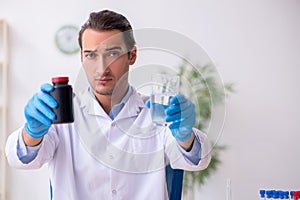 Young male lab assistant in drug synthesis concept