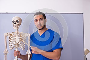Young male lecturer with skeleton in front of whiteboard