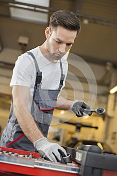 Young male maintenance engineer arranging tools in drawer at car workshop