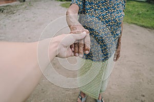 Young male man holding his grandmother hand with carefulness