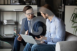 Young male manager explaining client contract details on laptop screen