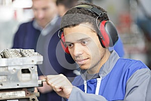 Young male manual worker wearing earmuffs at work