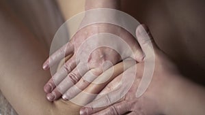 A young male masseur gives a professional massage to a client girl in a professional massage parlor. Action. Close up of