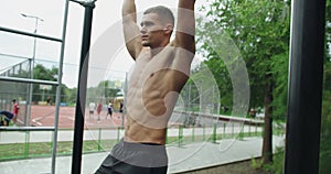 Young male with muscular body and six pack exercising at sport ground.