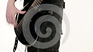 Young male musician in black clothes with a black bass guitar on a white background. Bass guitar player expressive music