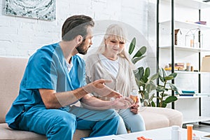young male nurse showing medicine to senior woman
