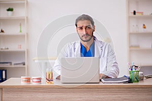 Young male odontologist in telemedicine concept photo