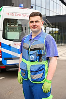 Young male paramedic stands by an ambulance