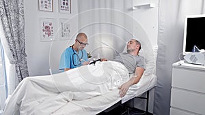 Young Male Patient Talking To Consultant In Emergency Room. Doctor examines a patient and takes notes in a notebook