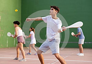 Young male pelota player hitting ball with wooden racket photo