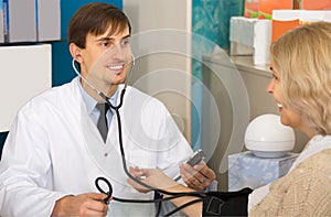 Young male pharmaceutist taking mature patients blood pressure